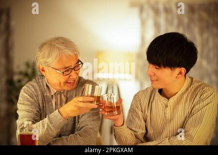 Un parent et un enfant font un toast avec du whisky Banque D'Images