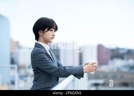 Femme d'affaires avec une expression sérieuse tenant une tasse de café Banque D'Images