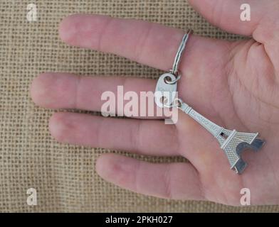 Main tenant une clé avec la Tour Eiffel en arrière-plan Banque D'Images