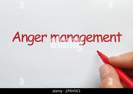 Homme écrivant l'expression Anger Management avec feutre rouge stylo pointe sur papier blanc, vue de dessus Banque D'Images