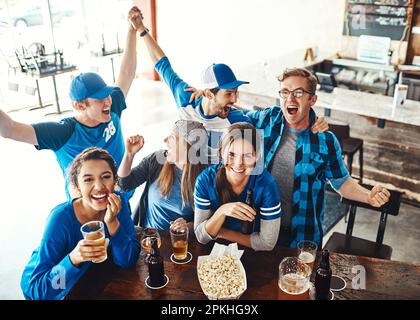 Super jeu, super compagnie. un groupe d'amis qui applaudissent tout en regardant un match sportif dans un bar. Banque D'Images