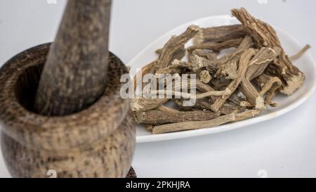 Mauvaise herbe de porc, diffusa de Boerhavia, racines séchées, sur un bol en céramique blanc. Banque D'Images