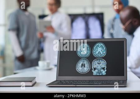 Gros plan de l'image radiologique du cerveau sur le moniteur de l'ordinateur portable avec un groupe de médecins travaillant en arrière-plan Banque D'Images