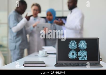 Gros plan de l'image de tomographie cérébrale sur le moniteur de l'ordinateur portable avec des médecins travaillant en équipe en arrière-plan Banque D'Images