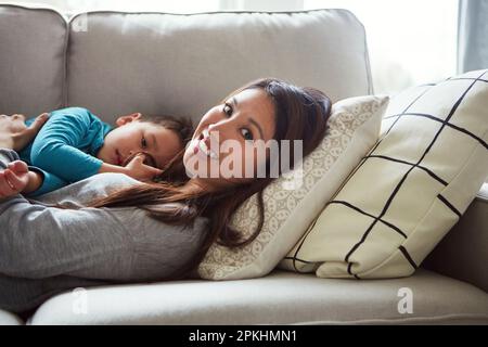 Le petit gars qui a volé mon cœur m'appelle maman. une jeune femme et son fils se détendent ensemble sur le canapé à la maison. Banque D'Images