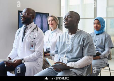 Groupe de médecins prenant des notes pendant la conférence médicale, ils sont assis sur des chaises et à l'écoute de l'orateur Banque D'Images