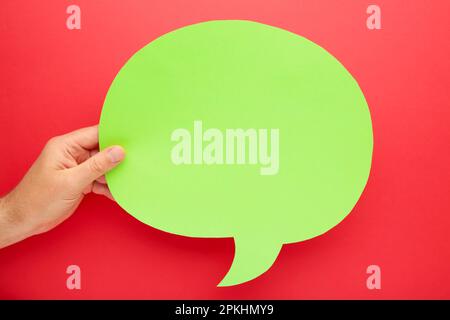 Main tenant une bulle de parole vide sur fond rouge. Vue de dessus Banque D'Images