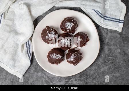 Biscuits aux noix de coco et aux pépites de chocolat. Produits de boulangerie. Biscuits avec thé sur fond sombre. Vue de dessus Banque D'Images