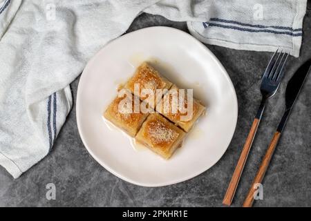 Baklava au lait et aux noisettes. Spécialités turques. Baklava au lait sur fond sombre. Nom local sutlu nuriye. Vue de dessus Banque D'Images