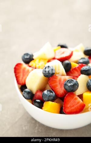 Salade de fruits frais dans un bol sur fond de béton gris. Aller à la verticale. Vue de dessus Banque D'Images