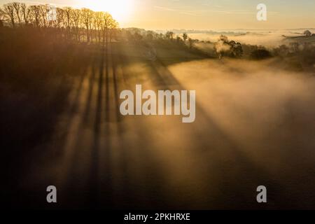 Le soleil levant projette des ombres dans la brume de la vallée de la Frome autour de Farleigh Hungerford, près de Bath. Date de la photo: Samedi 8 avril 2023. Banque D'Images