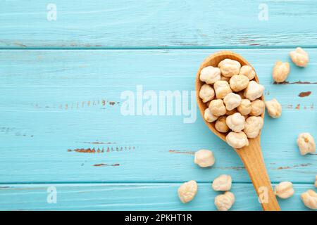 Pois chiches cuits dans la cuillère en bois sur fond bleu Banque D'Images