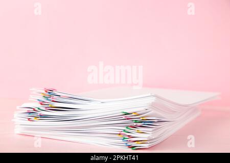 Trombone coloré avec pile de papier blanc sur papier rose. Vue de dessus Banque D'Images
