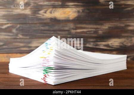 Trombone coloré avec pile de papier blanc sur marron. Vue de dessus Banque D'Images