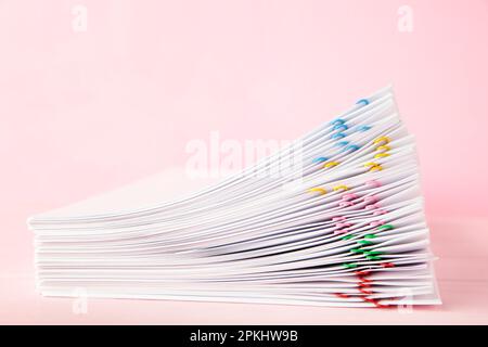 Trombone coloré avec pile de papier blanc sur papier rose. Vue de dessus Banque D'Images