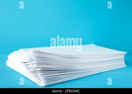 Trombone coloré avec pile de papier blanc sur bleu. Vue de dessus Banque D'Images