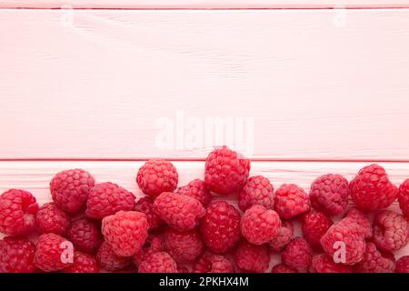 Framboises mûres sur fond de bois rose avec espace de copie. Vue de dessus Banque D'Images