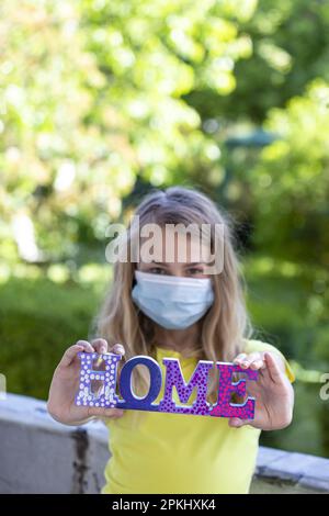 Fille (11) avec protection bouche-nez et lettrage à domicile, Kiel, Schleswig-Holstein, Allemagne Banque D'Images