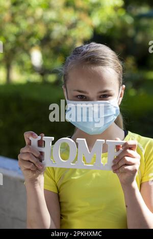 Fille (11) avec protection bouche-nez et lettrage à domicile, Kiel, Schleswig-Holstein, Allemagne Banque D'Images