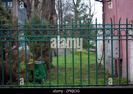 Une vieille clôture en métal forgé avec des pikes, des épingles, des anneaux de l'époque soviétique peints avec de la peinture verte. Banque D'Images