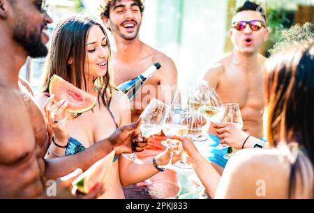 Groupe d'amis tendance buvant du champagne au vin blanc lors de la fête privée au bord de la piscine - concept de vacances de style de vie avec les jeunes hommes et femmes s'amusant Banque D'Images