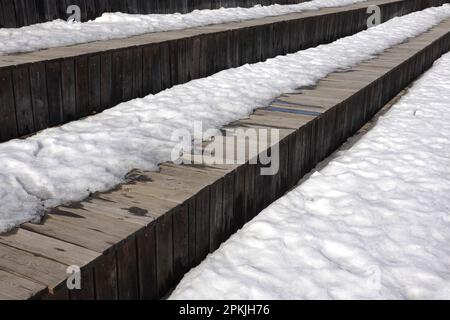 Fonce sur la neige de printemps sur les différentes surfaces des anciennes planches de bois brun surface extérieure vue latérale gros plan Banque D'Images