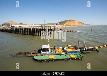 Un bateau de dragage en travaux dans le port de West Bay enlève le sable et les sédiments qui se sont accumulés au cours de l'hiver. West Bay Dorset Angleterre GB Banque D'Images