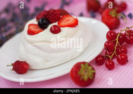 Mini-gâteau Pavlova dessert avec fraises fraîches, raisins de Corinthe noirs et rouges. Dessert d'été avec baies. Gâteau français. Meringue. Banque D'Images