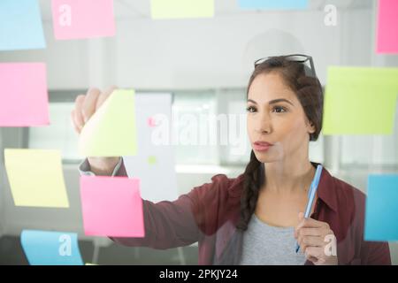 femme d'affaires créative lisant des notes adhésives Banque D'Images