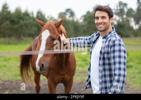 beau jeune homme prenant soin de cheval Banque D'Images