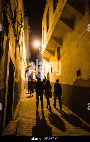 Un groupe de personnes se promènaient dans une ruelle étroite la nuit à Fès Maroc Banque D'Images