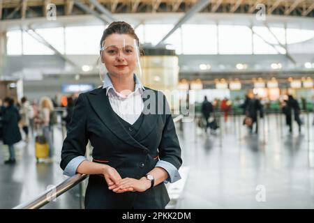 Une femme travaillant dans des vêtements habillés est debout à l'intérieur Banque D'Images