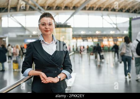 Une femme travaillant dans des vêtements habillés est debout à l'intérieur Banque D'Images