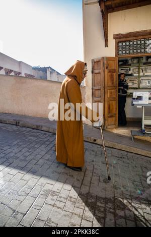 Un homme âgé portant une djellaba traditionnelle descend une rue de Fès Medina Maroc Banque D'Images