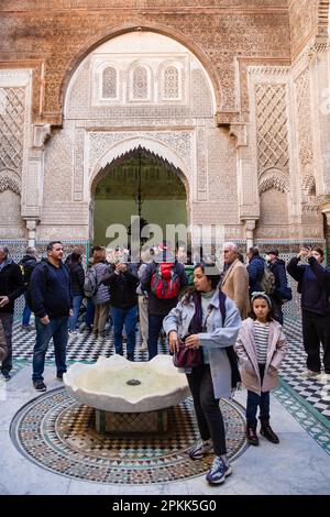 Les gens se rassemblent près de la fontaine en marbre dans la cour d'Al-Attarine Madrasa à Fès, au Maroc Banque D'Images