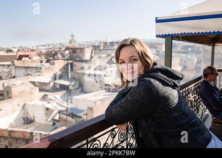 Une touriste américaine s'appuie sur une rambarde sur le toit surplombant la Médina du Maroc de Fès Banque D'Images