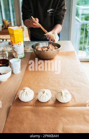 Une femme fait des Bao dans la cuisine. Bao, également connu sous le nom de baozi. C'est une cuisine chinoise traditionnelle. Banque D'Images