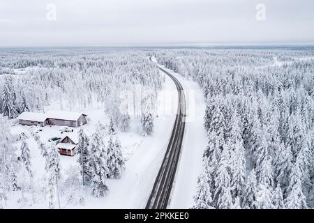 Route sinueuse traversant la forêt enneigée gelée, vue aérienne, Laponie, Finlande, Europe Banque D'Images