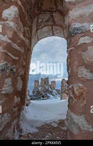 Le château enneigé de Rocca Calascio parmi les ruines du vieux village vu d'une arche, Rocca Calascio Banque D'Images