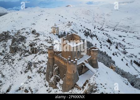 Vue aérienne rapprochée du château médiéval enneigé de Rocca Calascio et de l'église Santa Maria della Pieta au crépuscule Banque D'Images