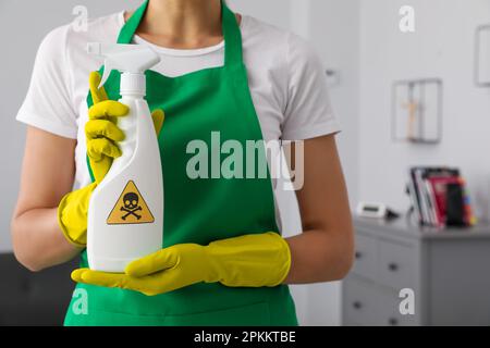 Femme présentant un spray chimique domestique toxique avec un panneau d'avertissement, gros plan Banque D'Images