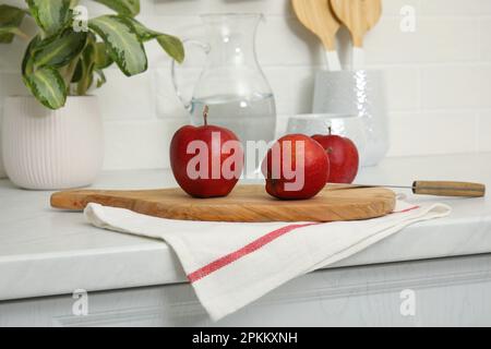 Une serviette propre et une planche en bois avec des pommes mûres sur le comptoir de la cuisine Banque D'Images