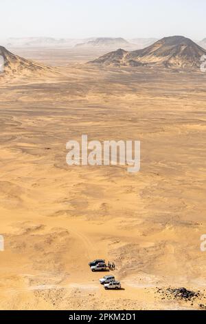 Jeeps garés à la base d'un basalte monte sur un plateau au désert noir en Égypte Banque D'Images