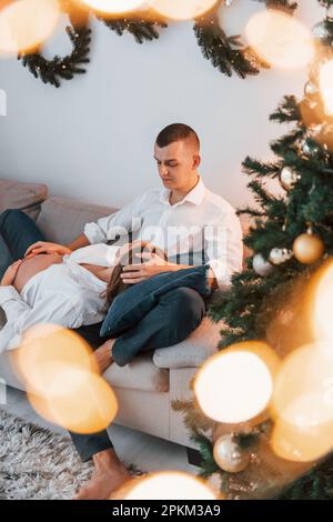 La femme est enceinte. Un couple charmant qui fête ses vacances ensemble à l'intérieur. Banque D'Images