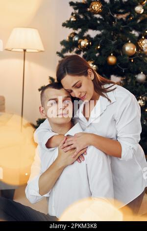 S'embrasser. Un couple charmant qui fête ses vacances ensemble à l'intérieur. Banque D'Images