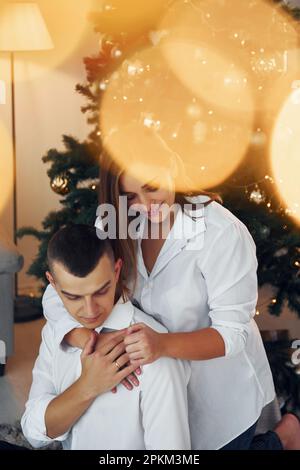 S'embrasser. Un couple charmant qui fête ses vacances ensemble à l'intérieur. Banque D'Images