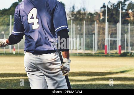 Vue arrière d'un joueur de baseball tenant une batte portant un uniforme d'équipe sur un terrain de sport Banque D'Images