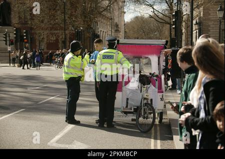 Des policiers parlent à un pilote de Rickshaw dans le centre de Londres Banque D'Images