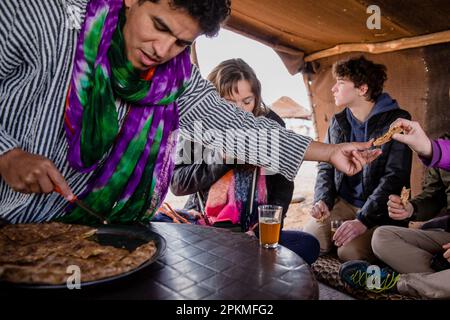 Un homme marocain passe des morceaux de pizza berbère à un touriste Banque D'Images