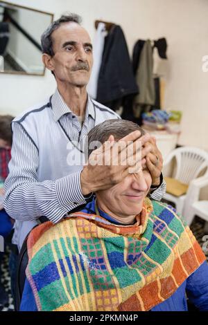 Un touriste américain qui se fait un rasoir droit et une coupe de cheveux dans un barbershop de Marrakech au Maroc Banque D'Images